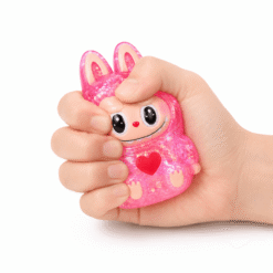 Main pressant un squishy personnage rose pailleté kawaii à texture ultra douce et à remontée lente.