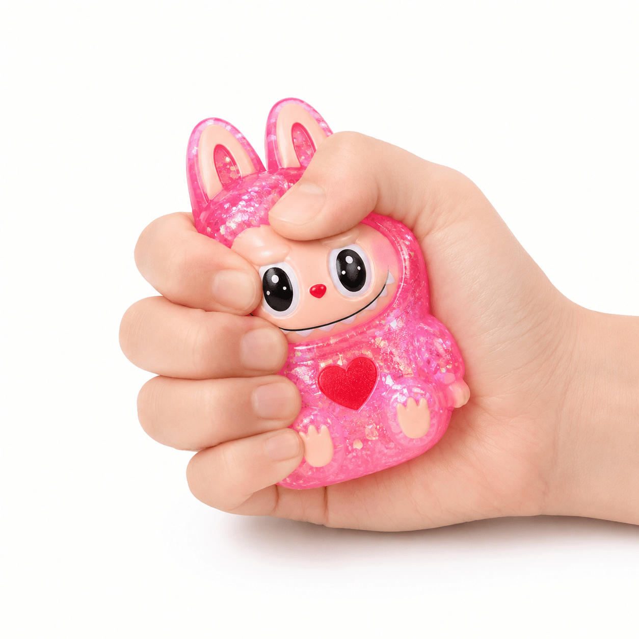 Main pressant un squishy personnage rose pailleté kawaii à texture ultra douce et à remontée lente.