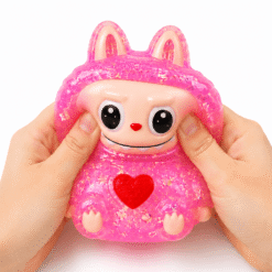 Main pressant un squishy personnage rose pailleté kawaii à texture ultra douce et à remontée lente.