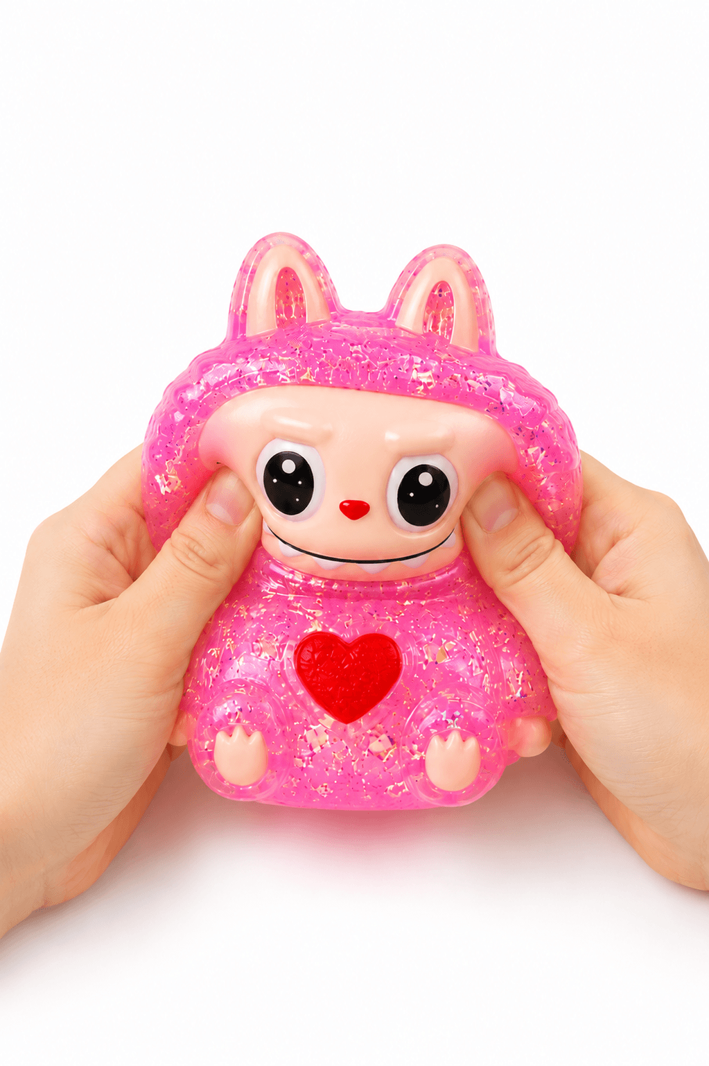 Main pressant un squishy personnage rose pailleté kawaii à texture ultra douce et à remontée lente.