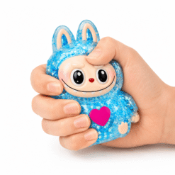 Main pressant un squishy personnage bleu pailleté kawaii à texture ultra douce et effet slow rising.